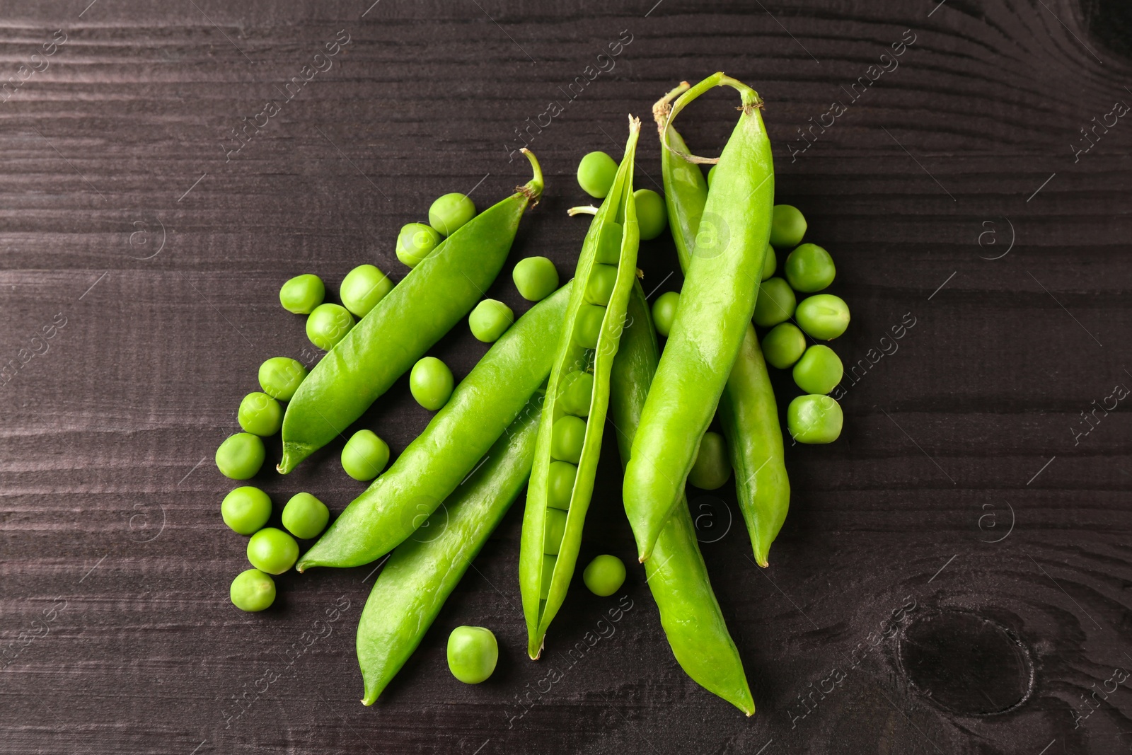 Photo of Fresh green peas and pods on black wooden table, top view