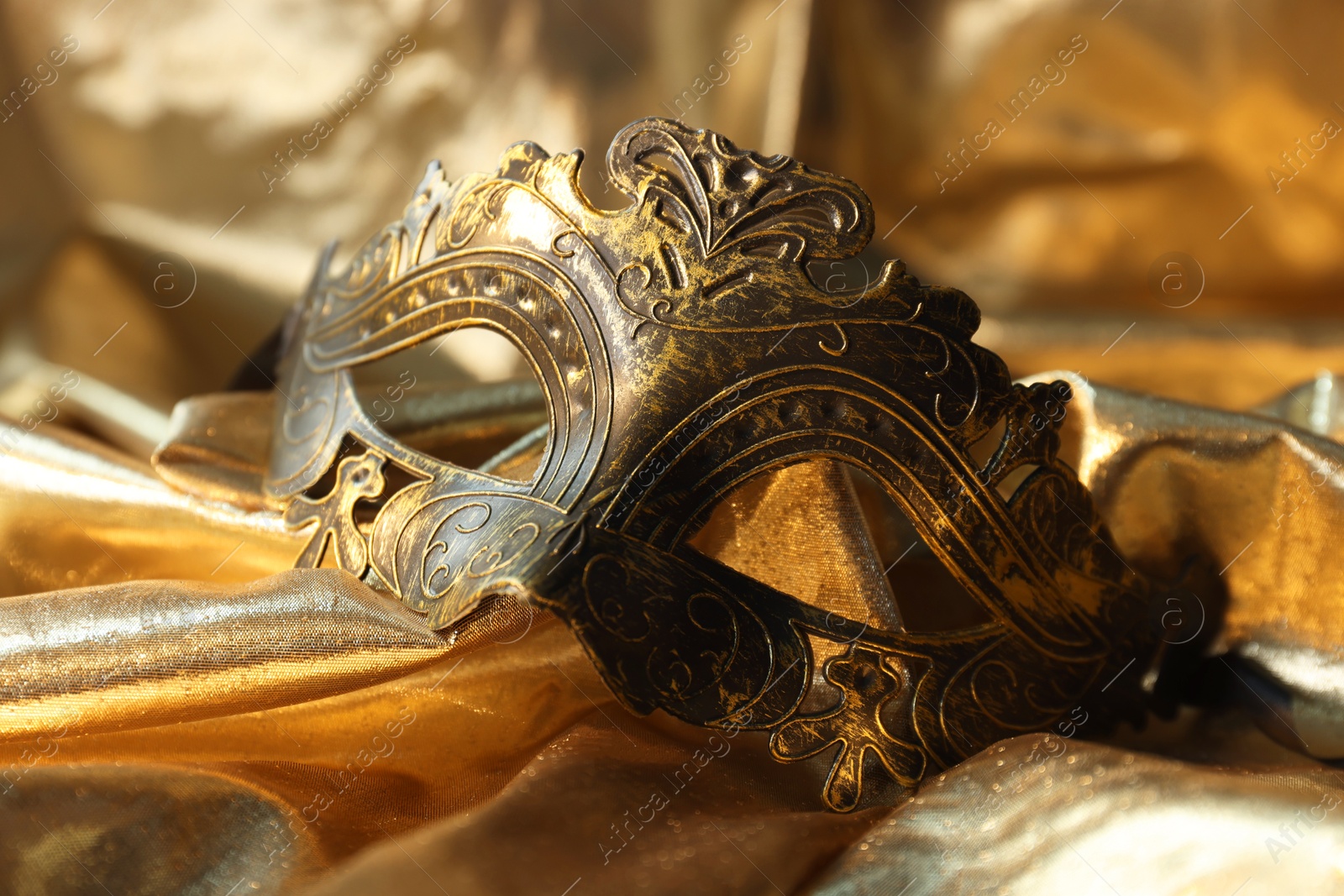 Photo of One beautiful carnival mask on golden fabric, closeup