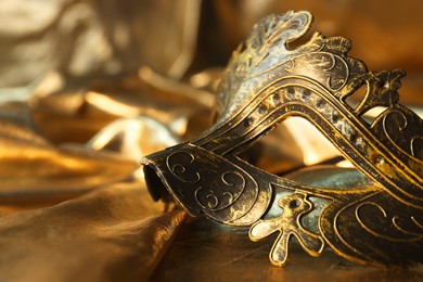 One beautiful carnival mask on golden fabric, closeup. Space for text