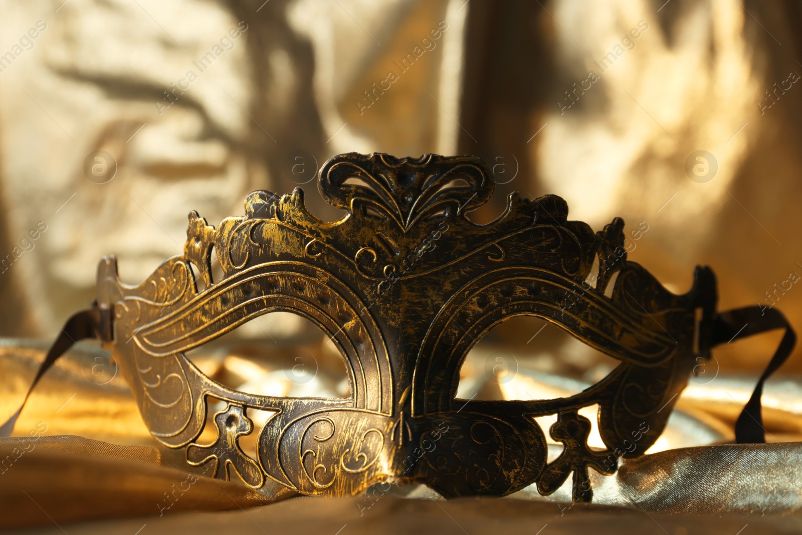 Photo of One beautiful carnival mask on golden fabric, closeup