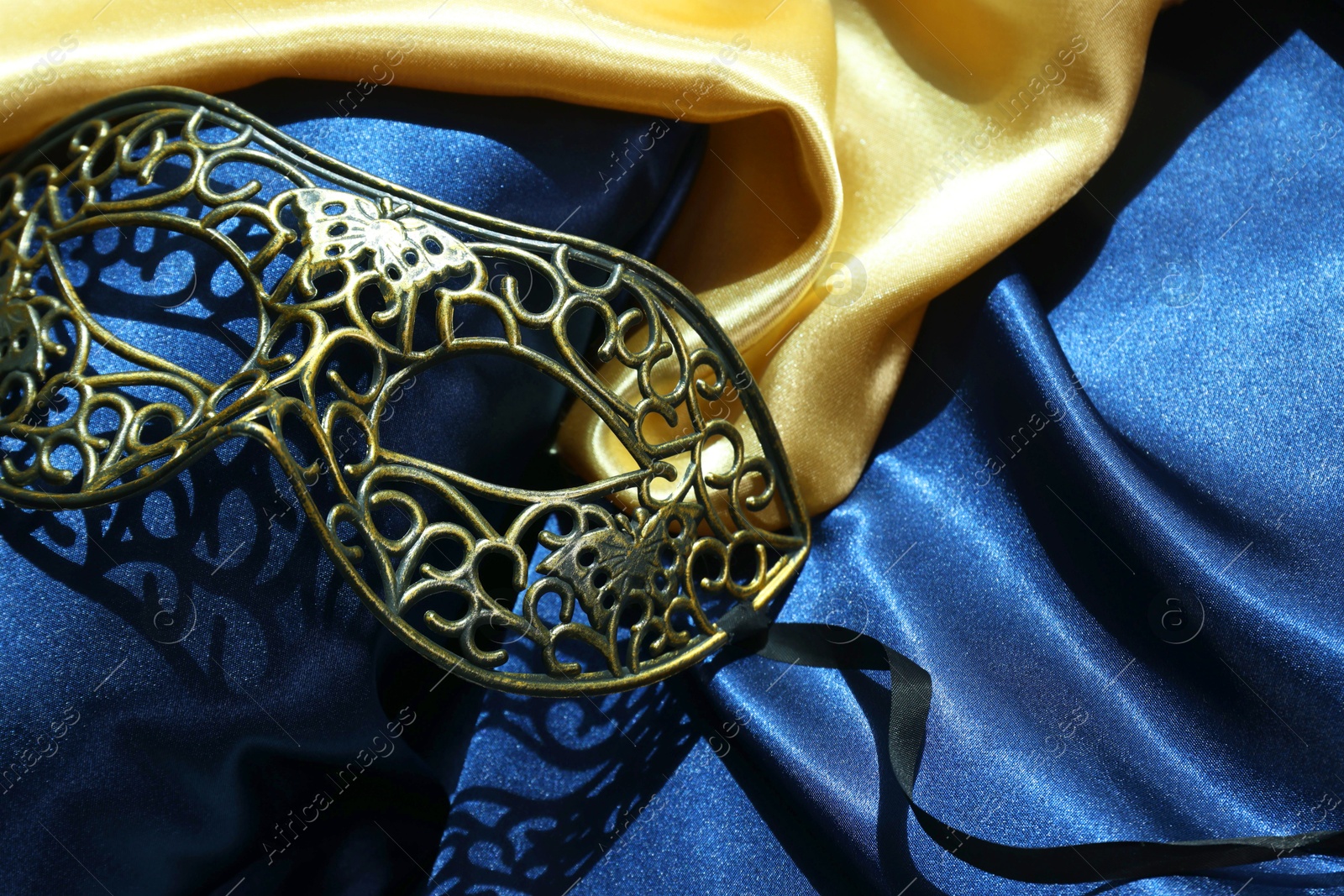 Photo of One beautiful carnival mask on blue fabric, above view