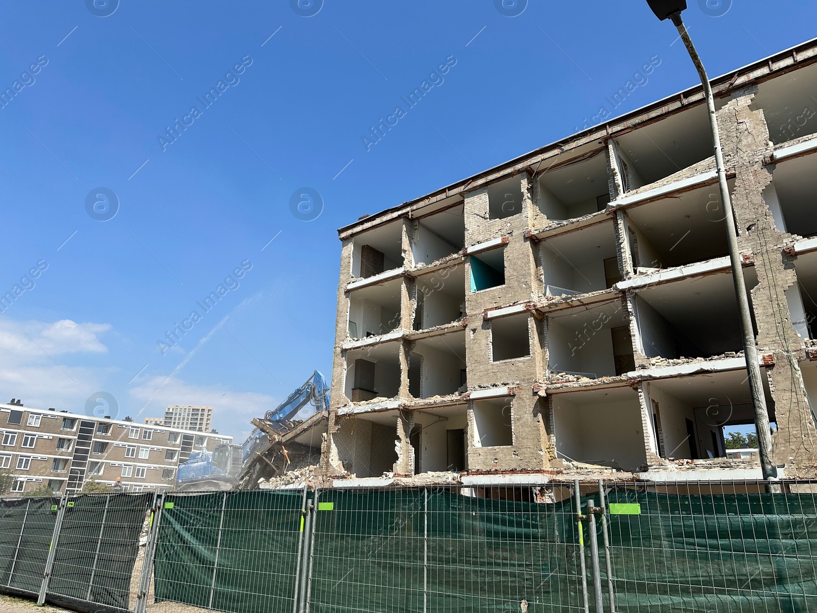 Photo of Demolition of building with excavator under blue sky