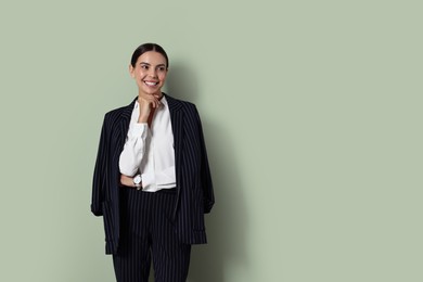 Beautiful woman in black striped suit on green background, space for text