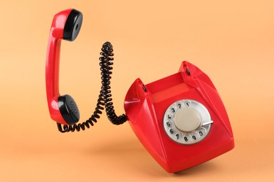 Photo of One red telephone with handset on pale orange background