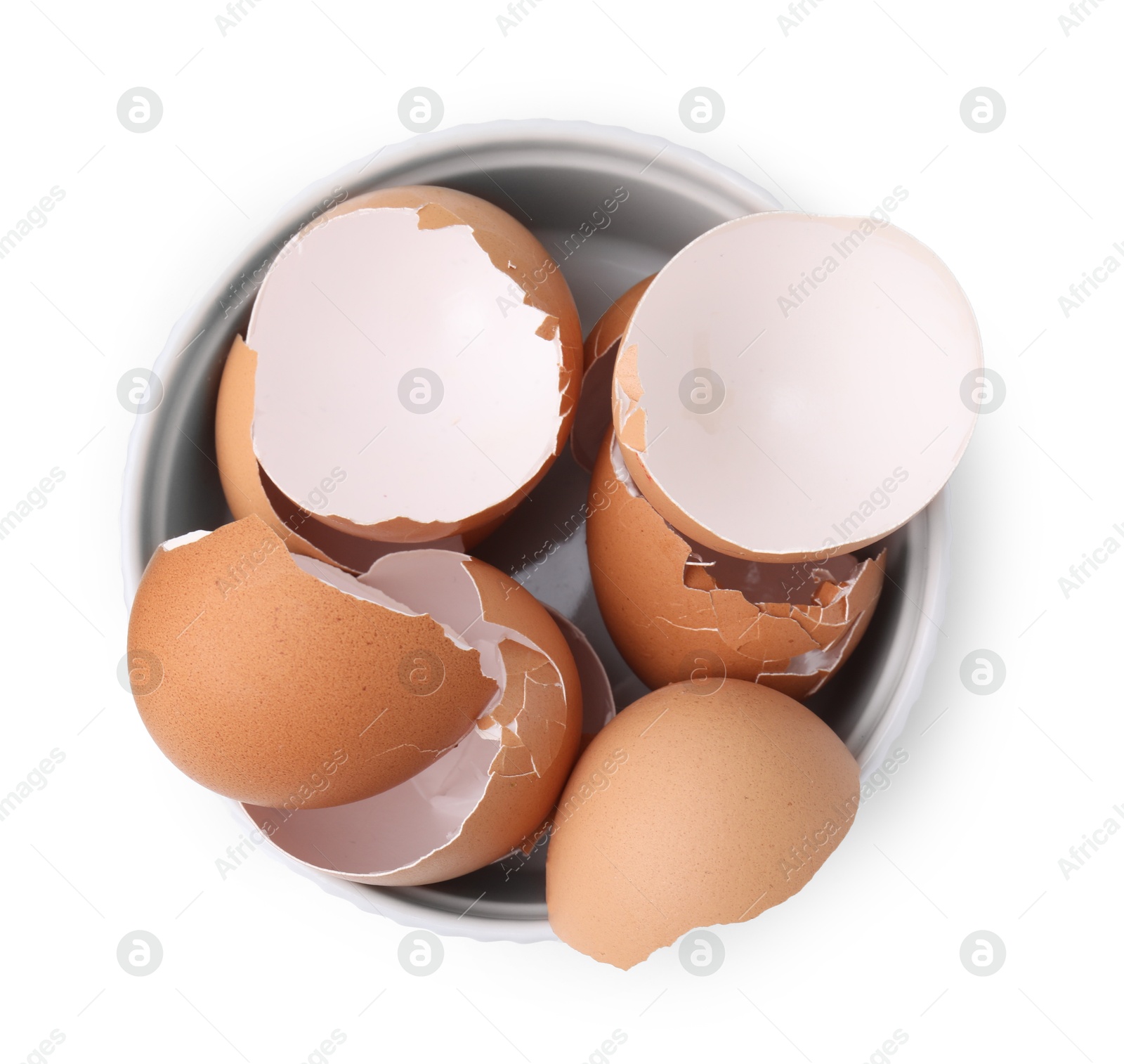 Photo of Broken eggshells in bowl isolated on white, top view