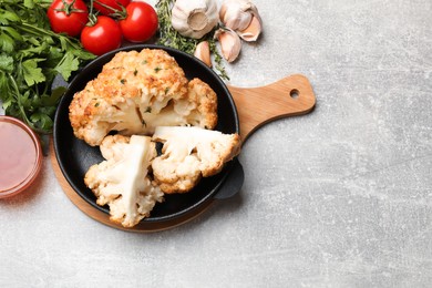 Photo of Delicious baked cauliflower in baking dish and products on gray textured table, flat lay. Space for text