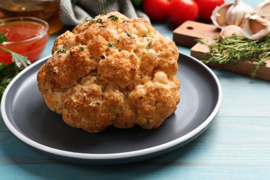 Photo of Delicious baked cauliflower and products on light blue wooden table, closeup