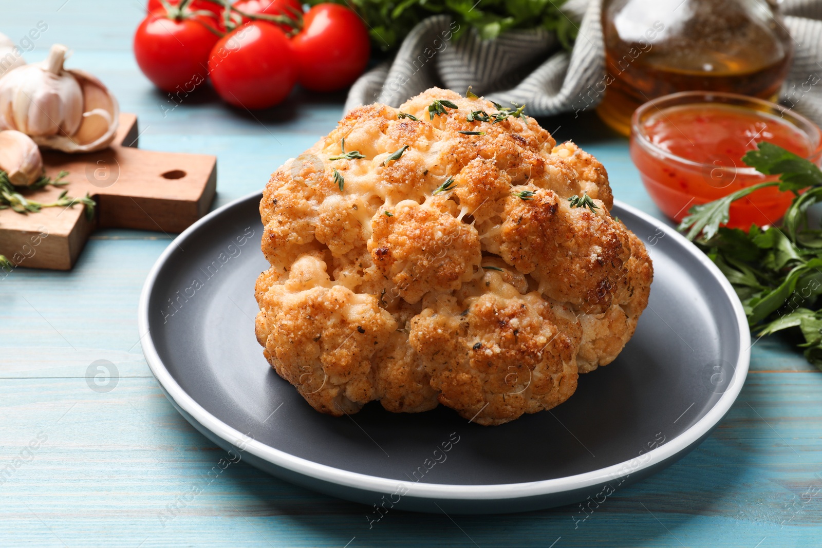 Photo of Delicious baked cauliflower and products on light blue wooden table