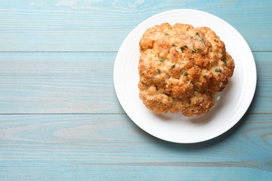 Delicious baked cauliflower on light blue wooden table, top view. Space for text