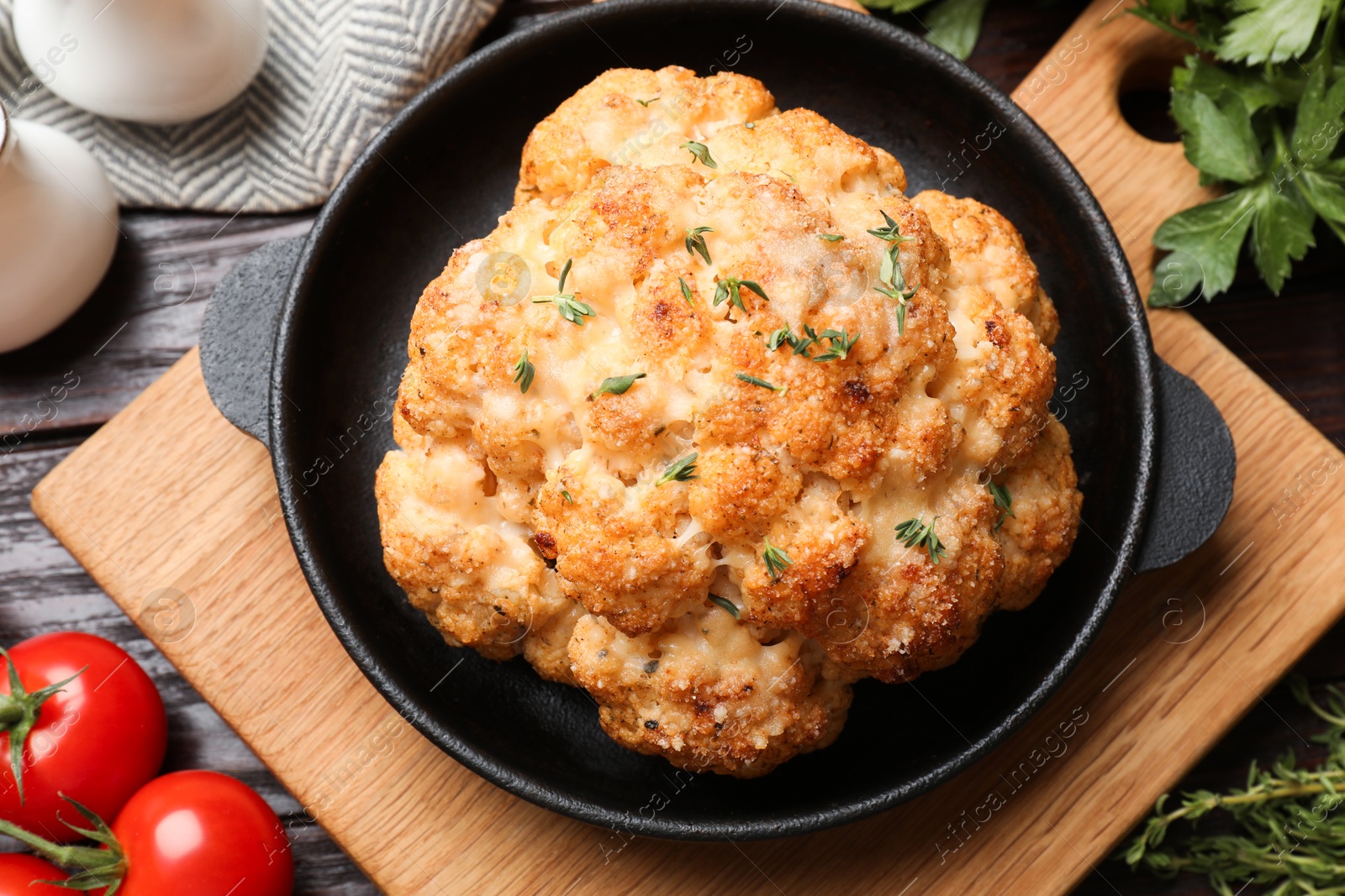 Photo of Delicious baked cauliflower in baking dish and products on wooden table, flat lay