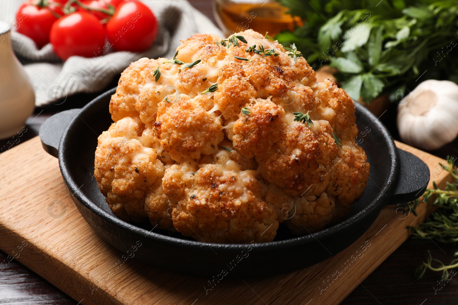 Photo of Delicious baked cauliflower in baking dish on wooden table, closeup