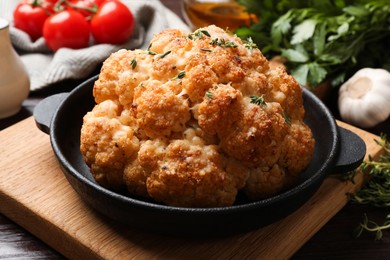 Delicious baked cauliflower in baking dish on wooden table, closeup