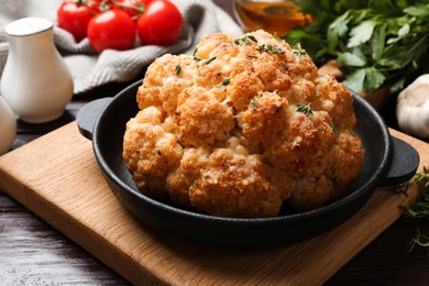 Delicious baked cauliflower in baking dish on wooden table, closeup