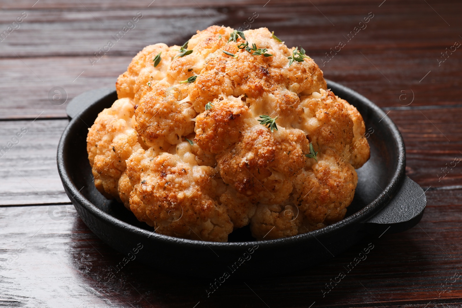 Photo of Delicious baked cauliflower in baking dish on wooden table, closeup