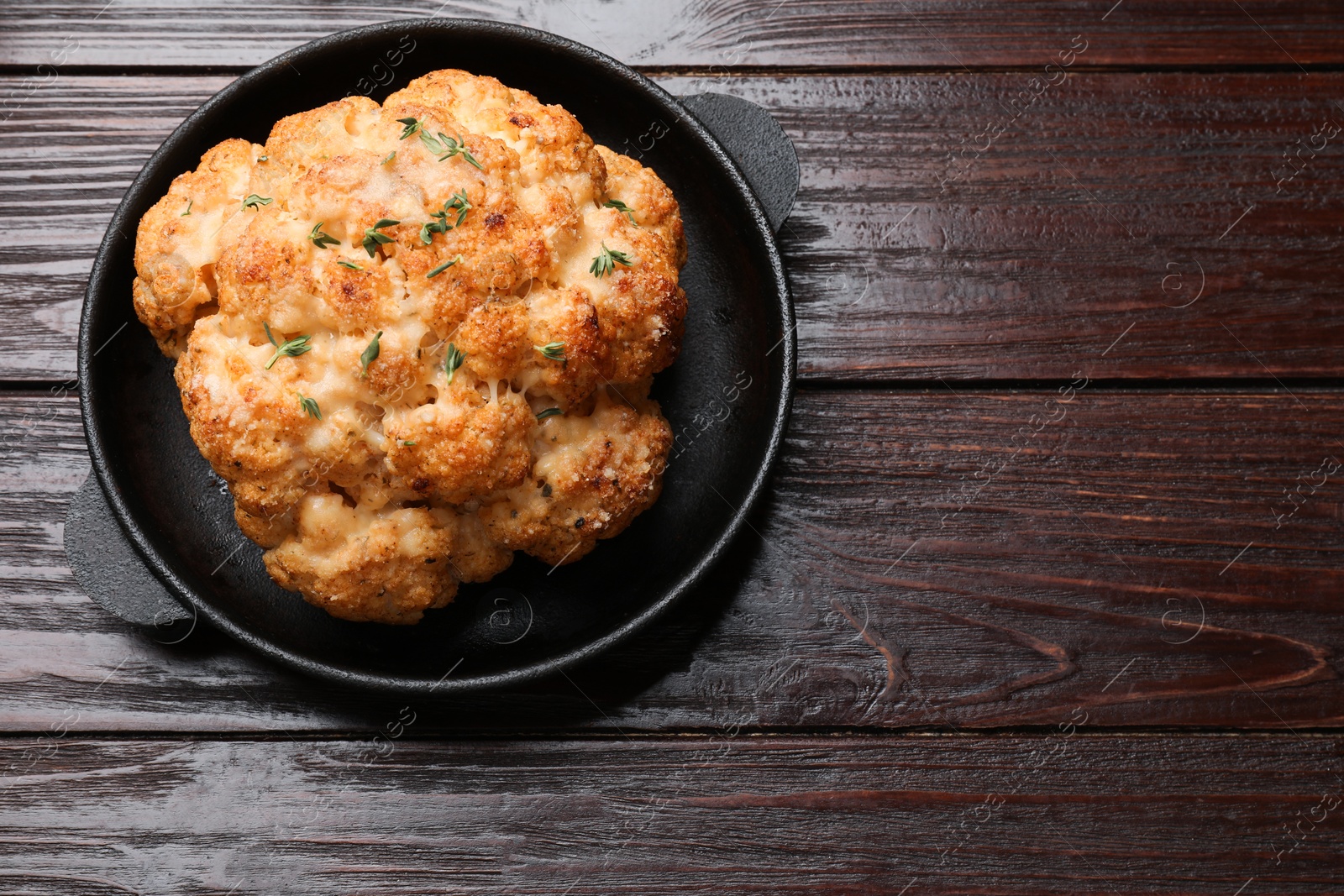 Photo of Delicious baked cauliflower in baking dish on wooden table, top view. Space for text