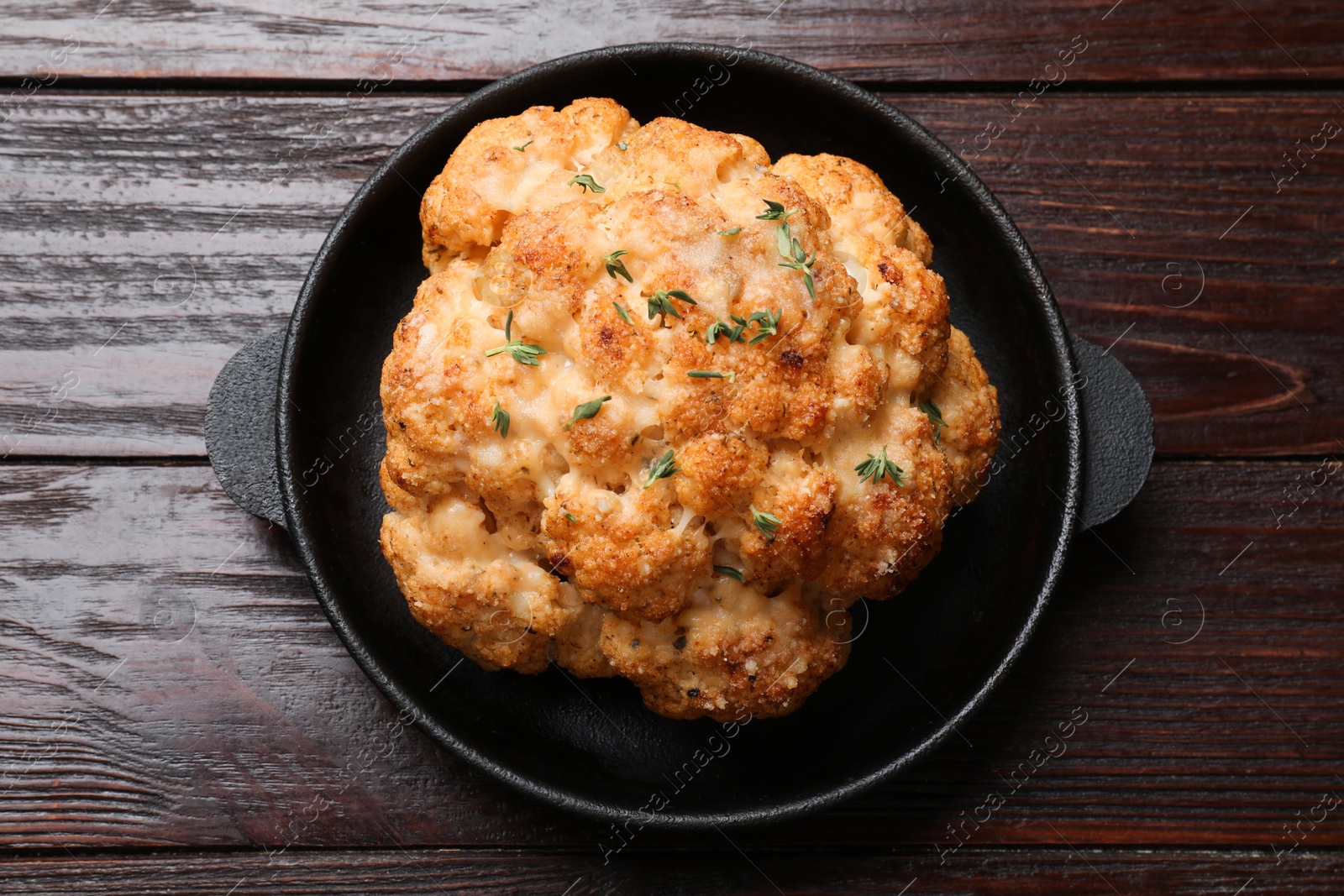 Photo of Delicious baked cauliflower in baking dish on wooden table, top view