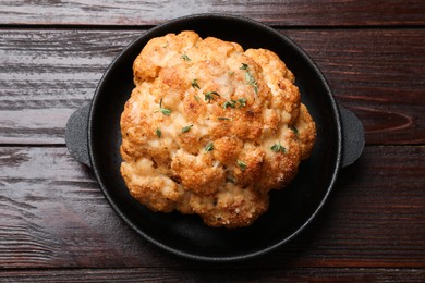 Delicious baked cauliflower in baking dish on wooden table, top view