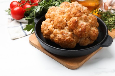 Delicious baked cauliflower in baking dish and products on white table, closeup