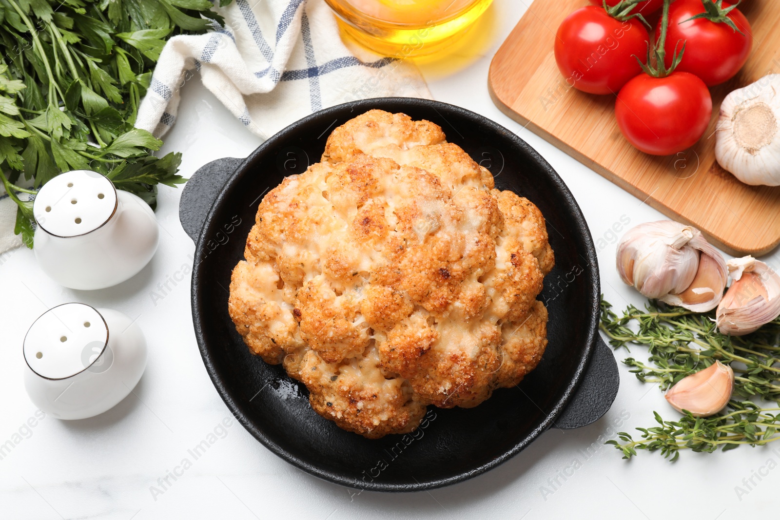 Photo of Delicious baked cauliflower in baking dish and products on white table, flat lay