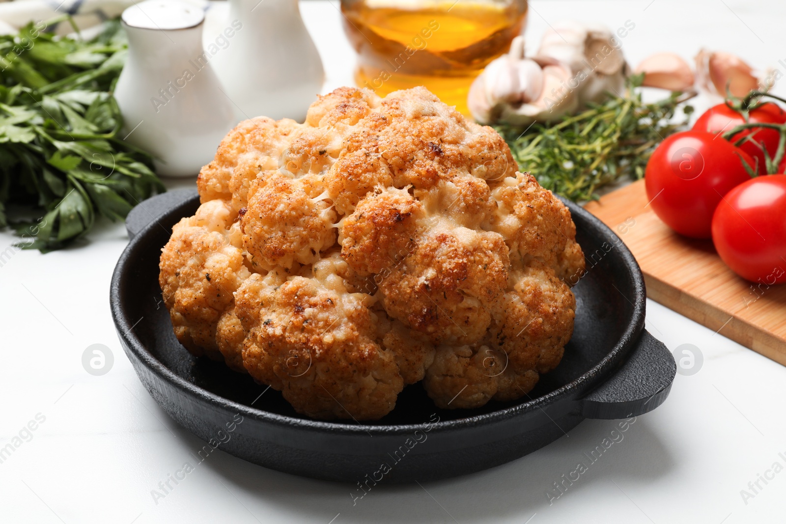 Photo of Delicious baked cauliflower in baking dish and products on white table, closeup