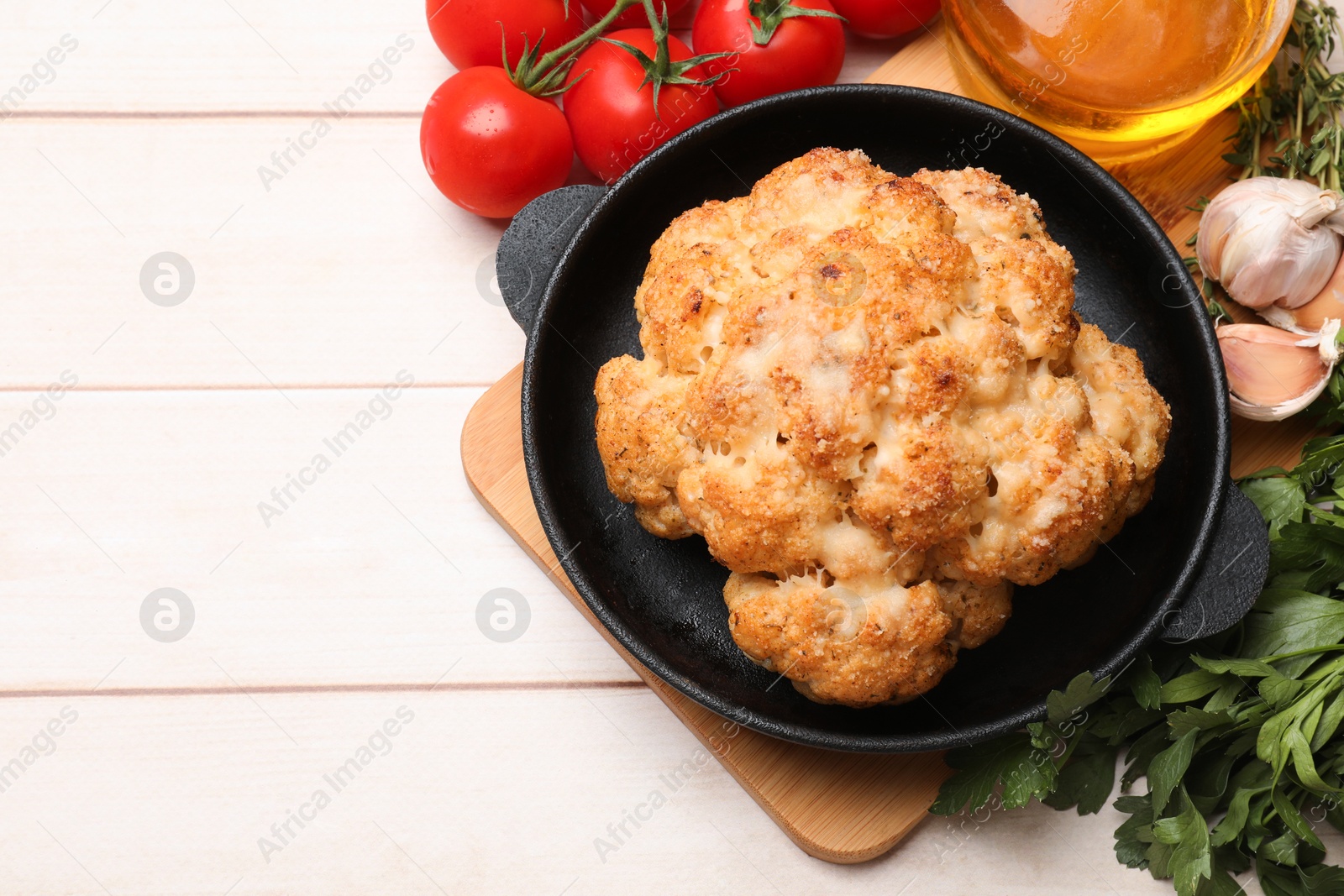 Photo of Delicious baked cauliflower, tomatoes and spices on wooden table, flat lay. Space for text