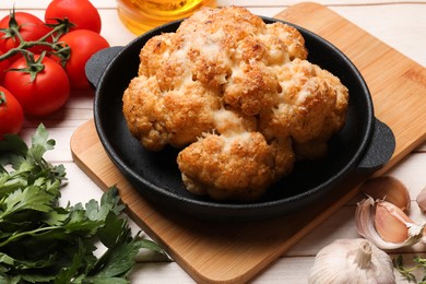 Delicious baked cauliflower, tomatoes and spices on wooden table, closeup