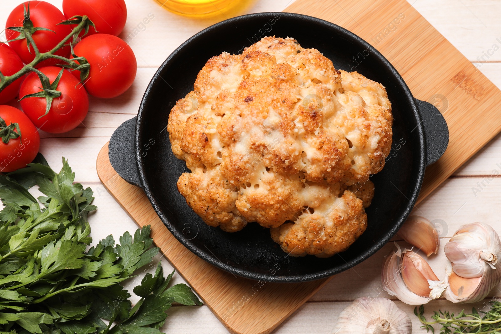 Photo of Delicious baked cauliflower, tomatoes and spices on wooden table, flat lay