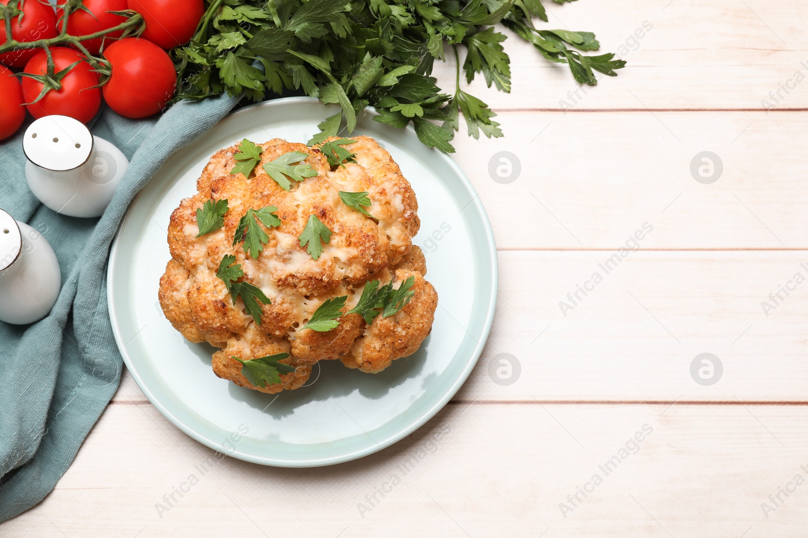 Photo of Delicious baked cauliflower, tomatoes and spices on wooden table, flat lay. Space for text