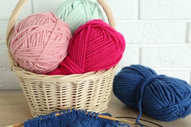 Photo of Bright yarns, knitting needles and pattern sample on wooden shelf indoors, closeup