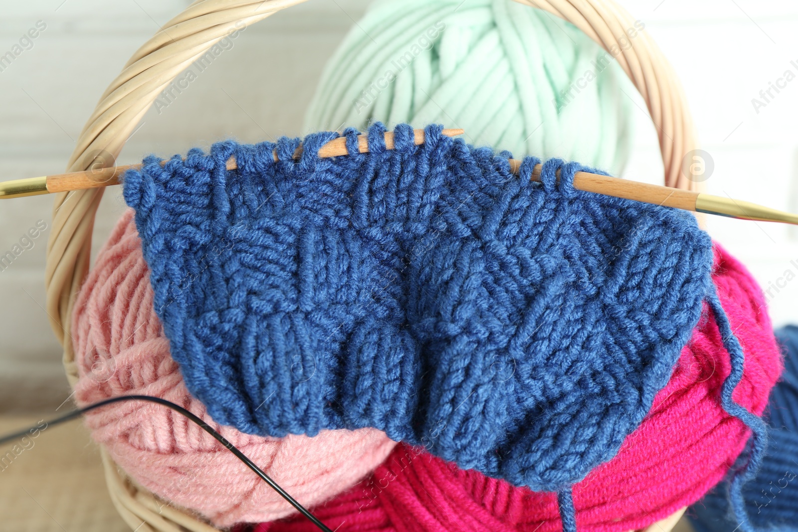 Photo of Knitting needles, pattern sample and yarns indoors, closeup