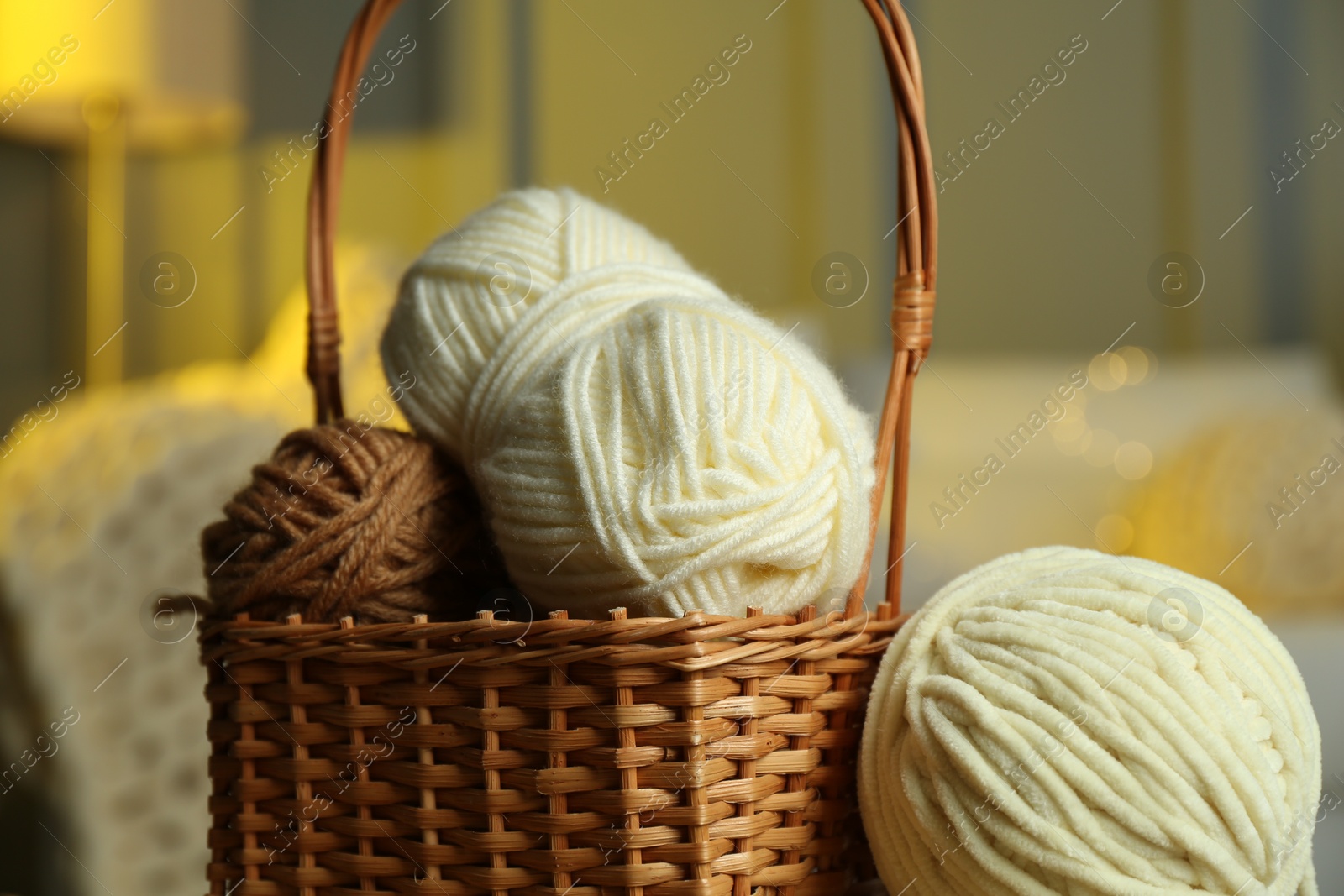 Photo of Wicker basket with colorful yarns on blurred background, closeup