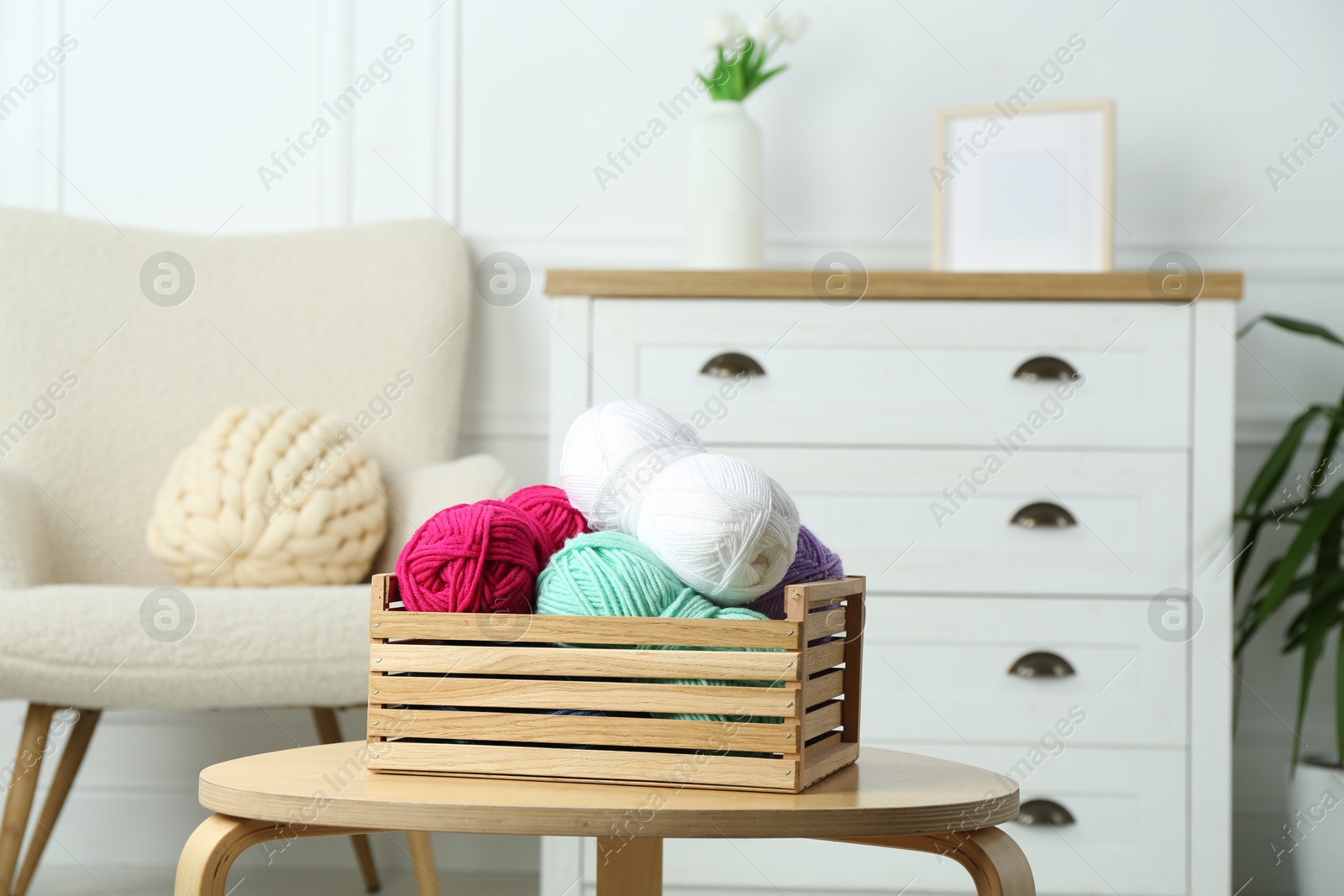 Photo of Wooden crate with different yarns on coffee table indoors