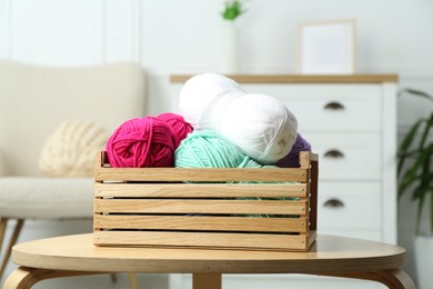 Photo of Wooden crate with different yarns on coffee table indoors