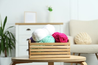 Wooden crate with different yarns on coffee table indoors