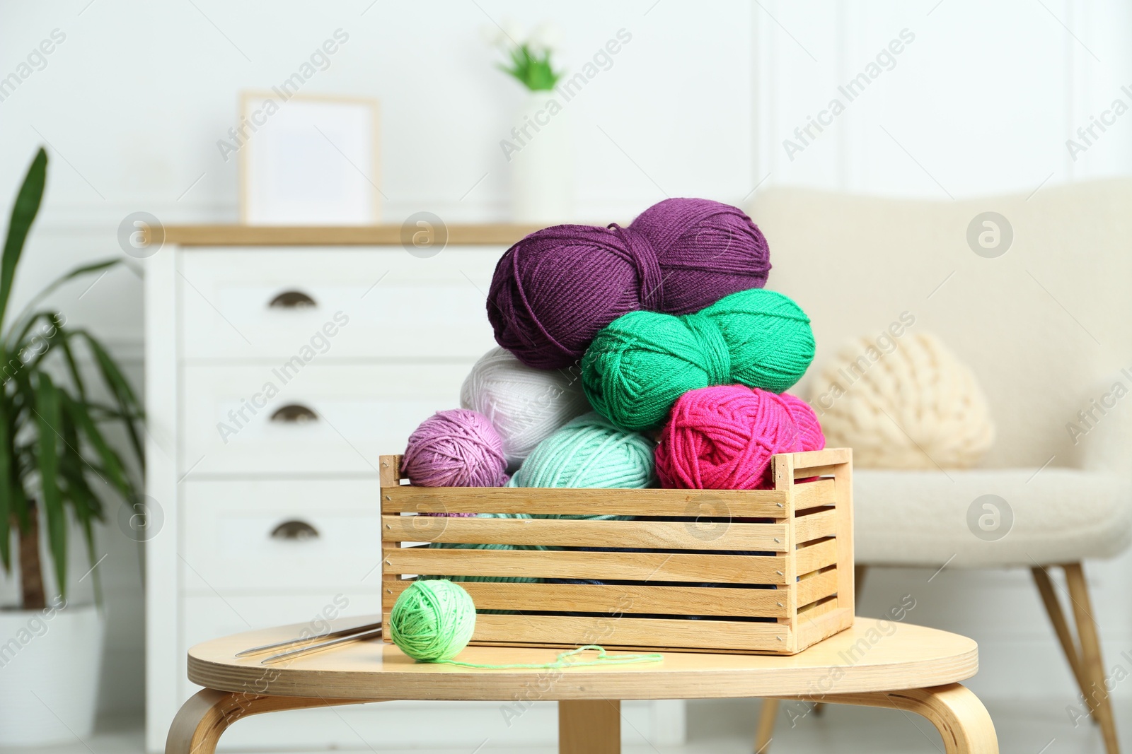 Photo of Wooden crate with different yarns on coffee table indoors