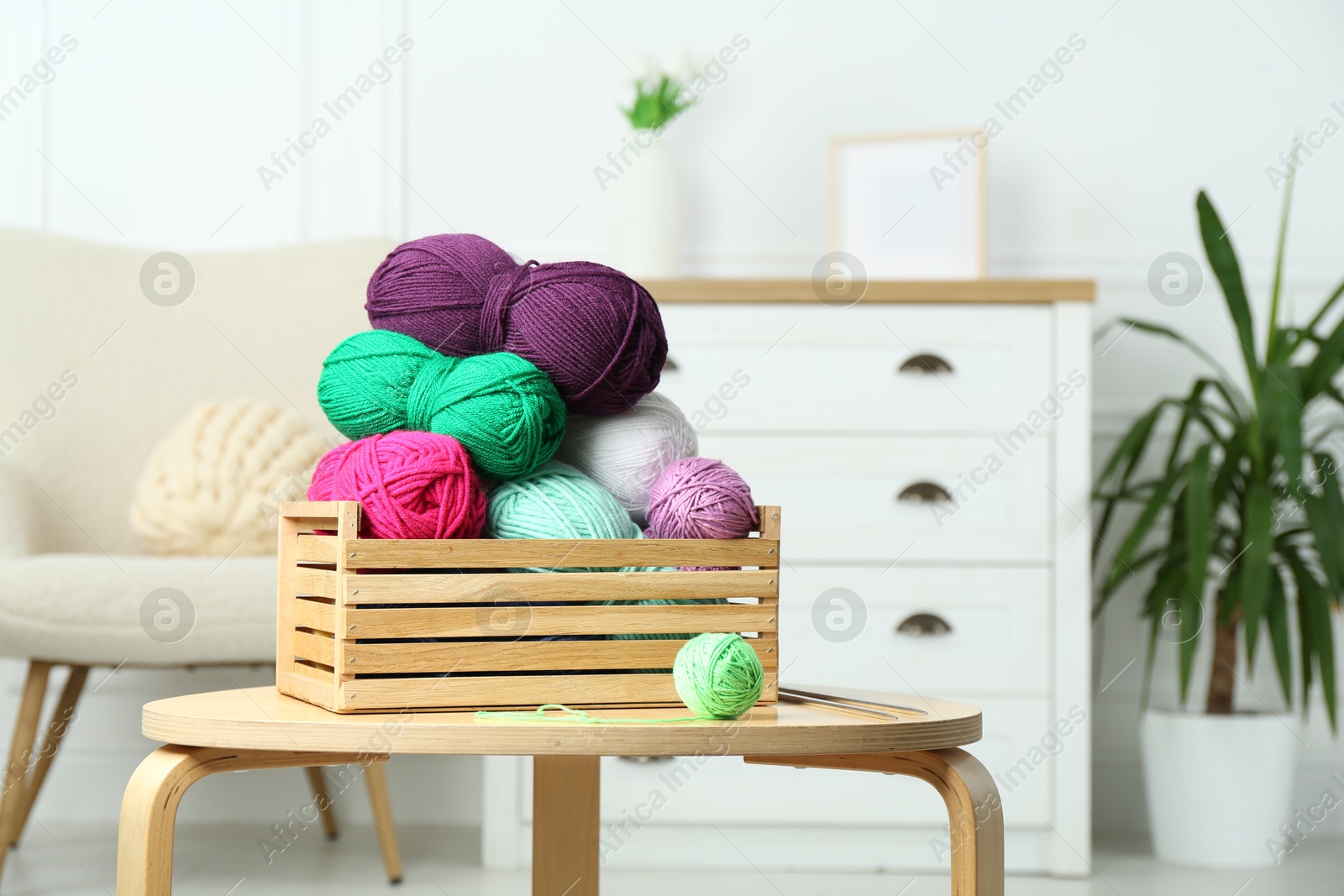 Photo of Wooden crate with different yarns on coffee table indoors