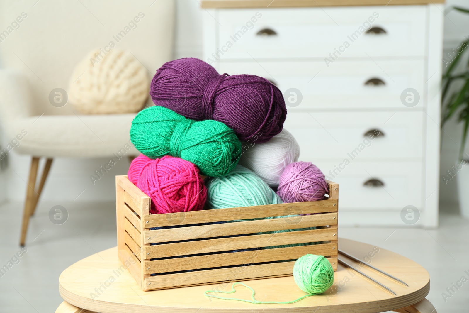 Photo of Wooden crate with different yarns on coffee table indoors