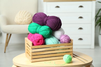 Photo of Wooden crate with different yarns on coffee table indoors