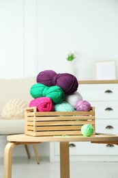 Wooden crate with different yarns on coffee table indoors