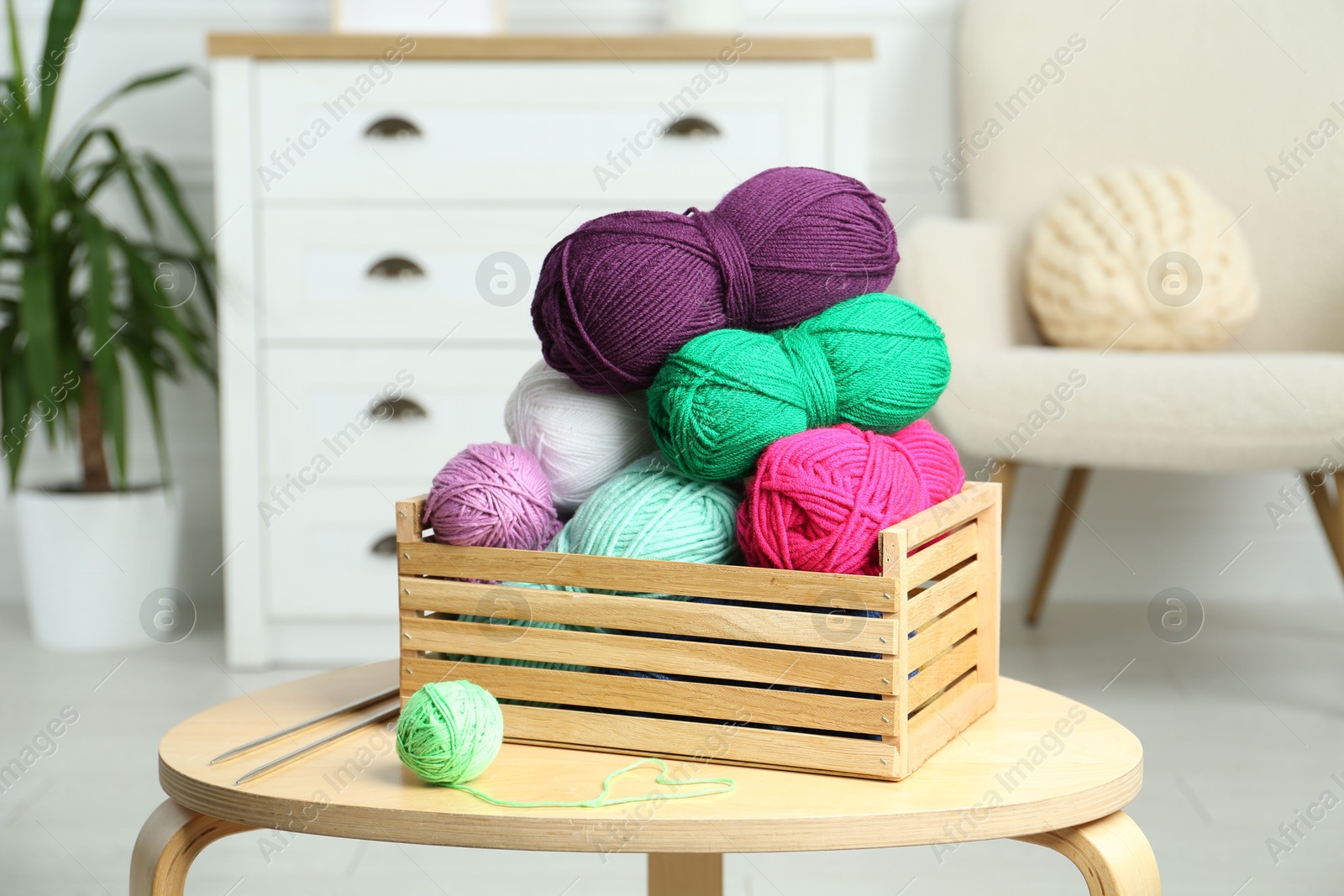 Photo of Wooden crate with different yarns on coffee table indoors