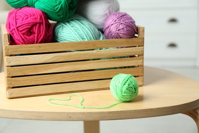 Wooden crate with different yarns on coffee table indoors