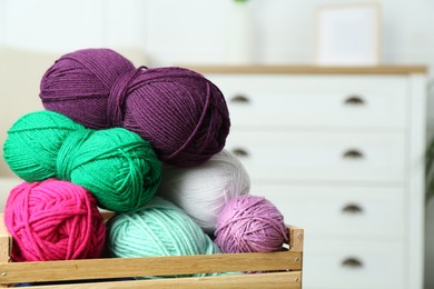 Photo of Wooden crate with different yarns on blurred background. Space for text