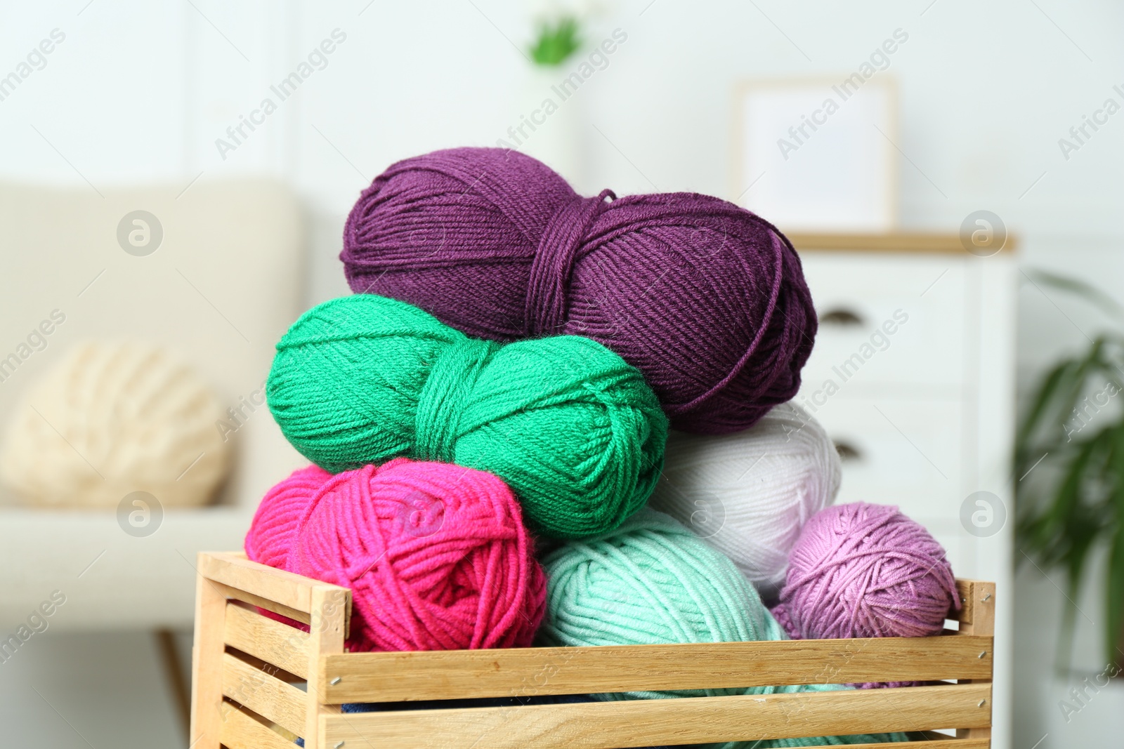 Photo of Wooden crate with different yarns on blurred background