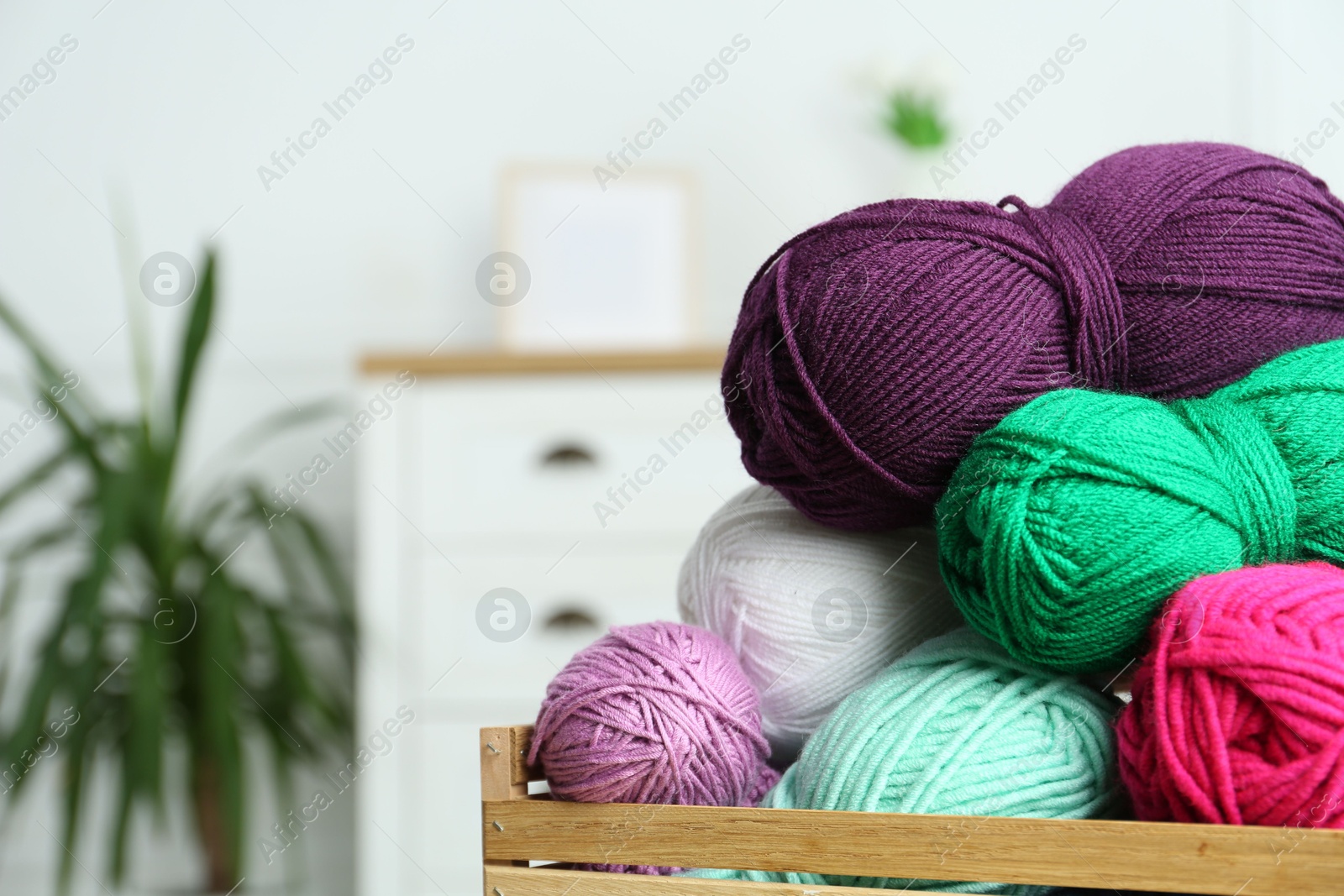 Photo of Wooden crate with different yarns on blurred background. Space for text