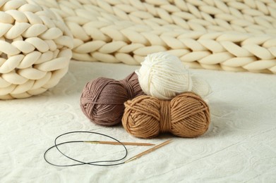 Photo of Skeins of yarn and knitting needles on soft blanket