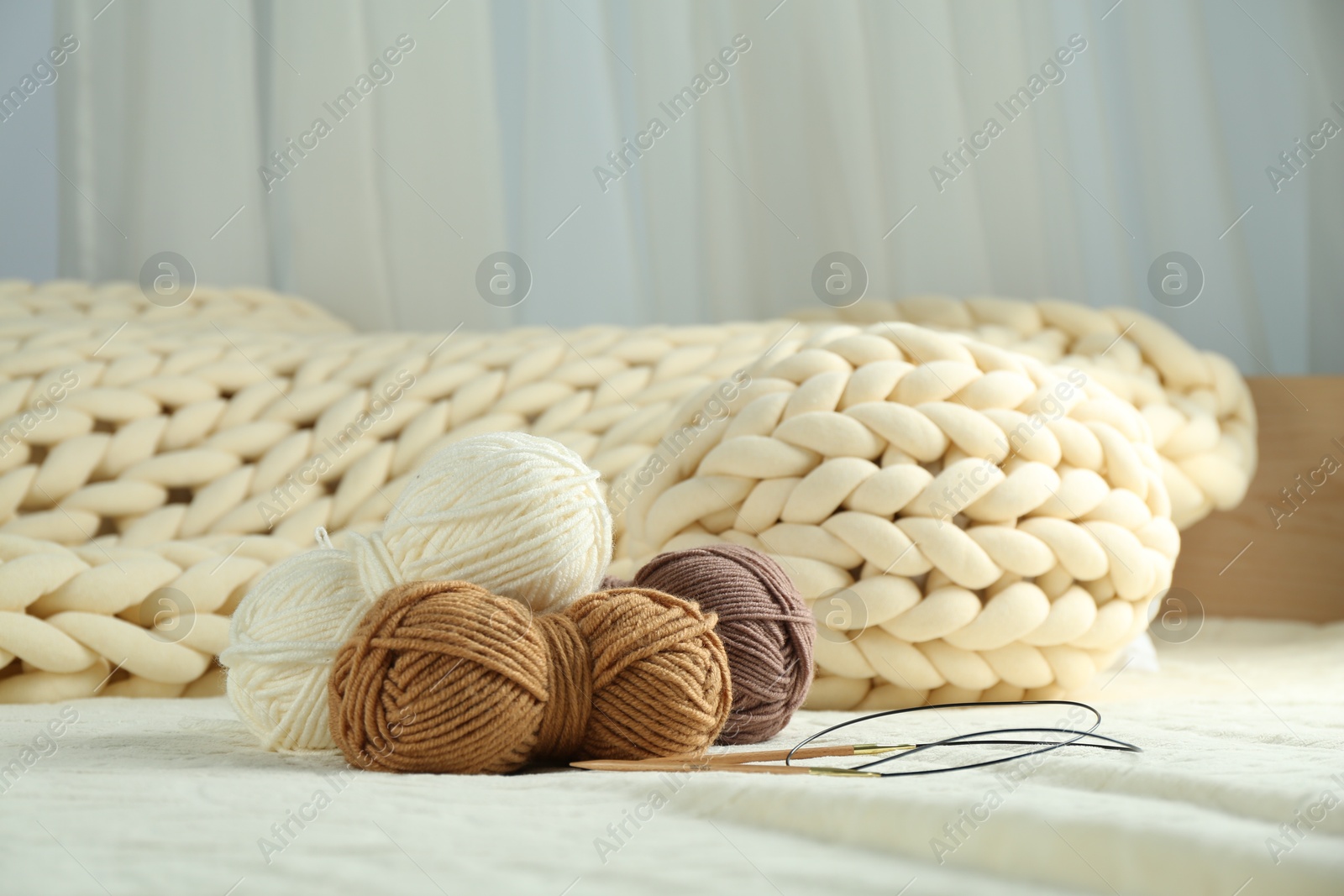 Photo of Skeins of yarn and knitting needles on soft blanket