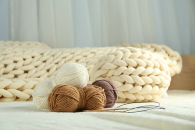 Skeins of yarn and knitting needles on soft blanket