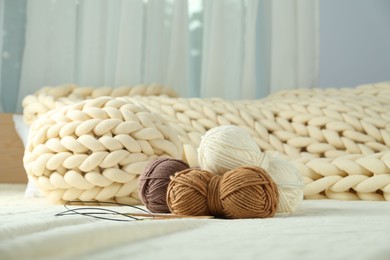 Photo of Skeins of yarn and knitting needles on soft blanket