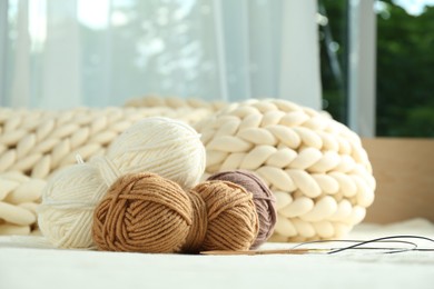 Photo of Skeins of yarn and knitting needles on soft blanket