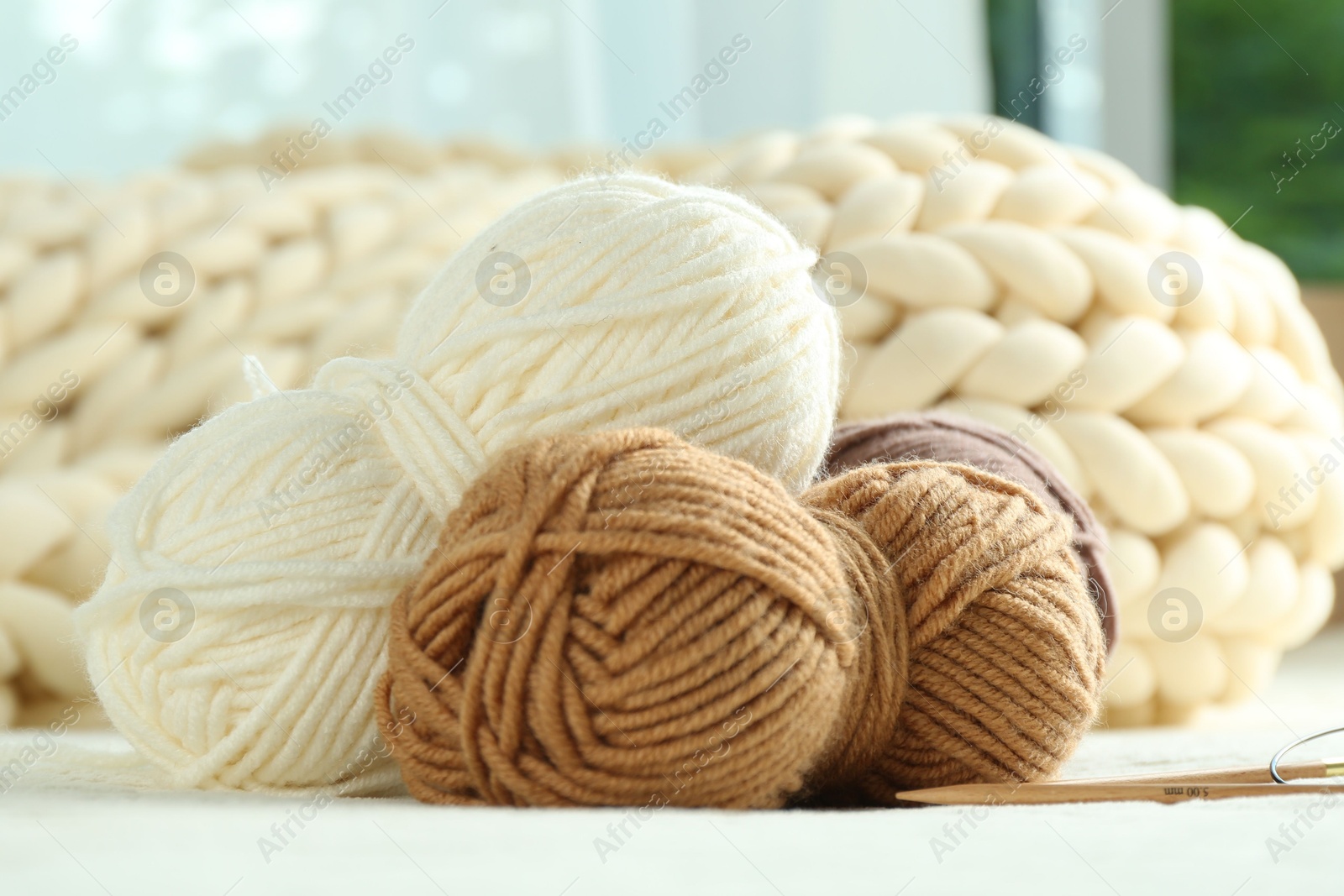 Photo of Skeins of yarn and knitting needles on soft blanket, closeup